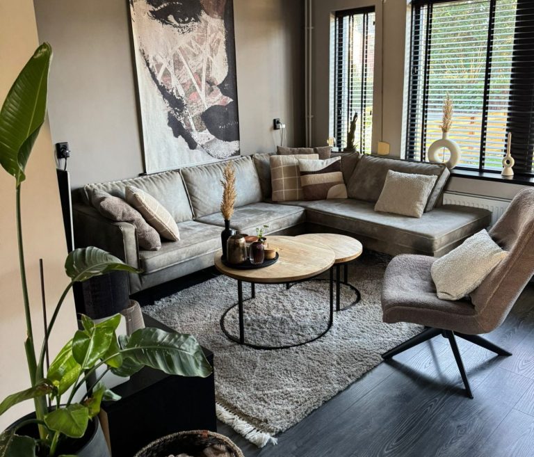 Een moderne woonkamer met een grote bank, een ronde tafel en kunst aan de muur.